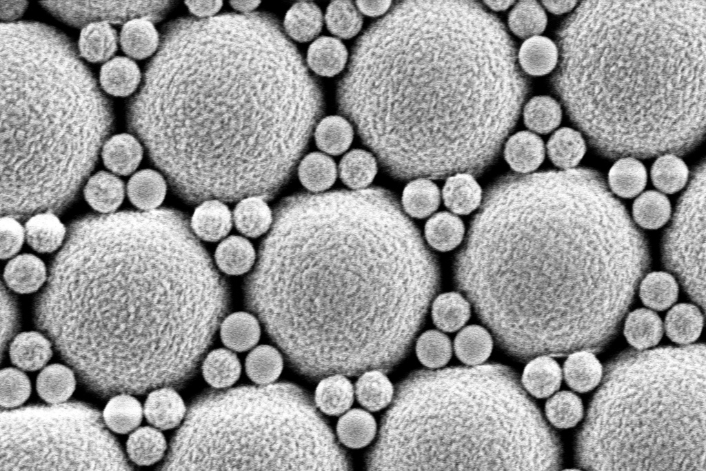 The electron micrograph shows a hexagonally arranged structure of spheres of different sizes.